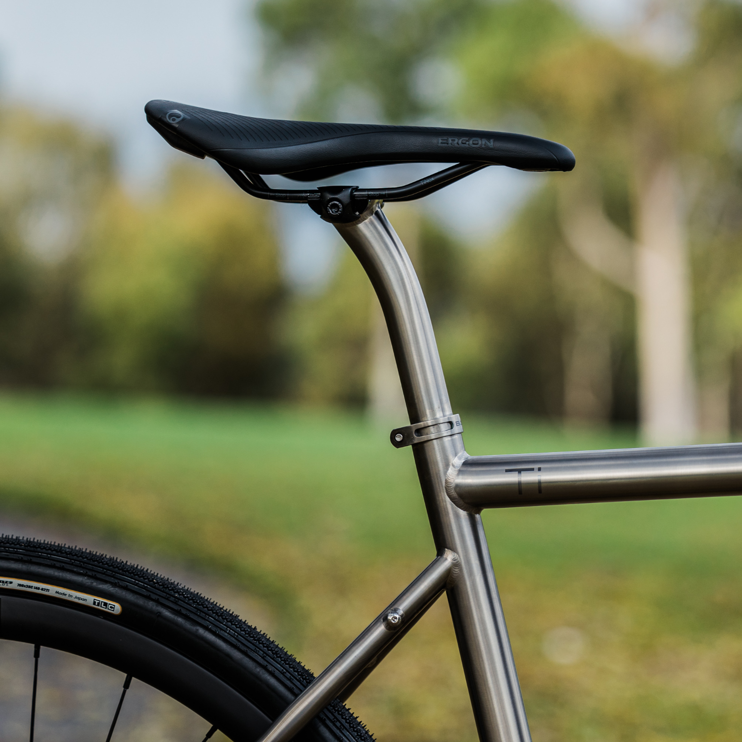 Side view of a Ergon SR Pro Men’s saddle mounted to a titanium Bossi bike, shot outdoors in a park