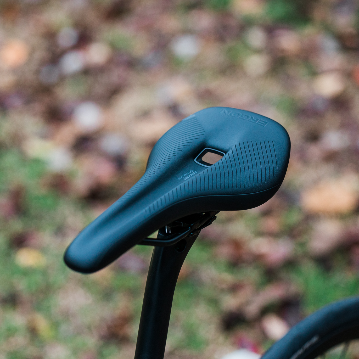 Angled top view of a Ergon SR Pro Men’s saddle mounted to a Bossi bike, shot outdoors against a leafy background