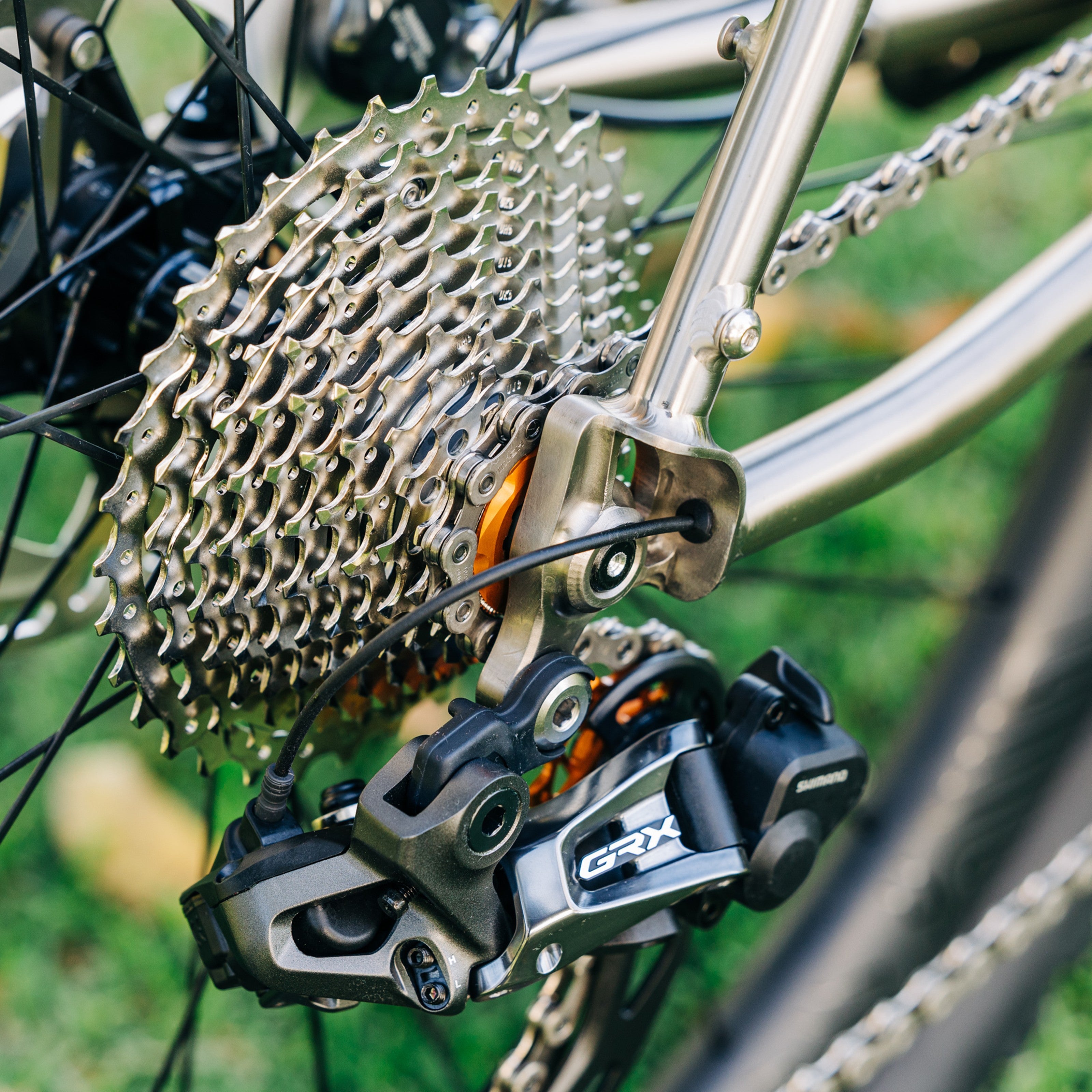 Close-up of Garbaruk orange cassette lockring fitted to a Bossi titanium bike, demonstrating clean integration with cassette plus a pop of colour for the drivetrain