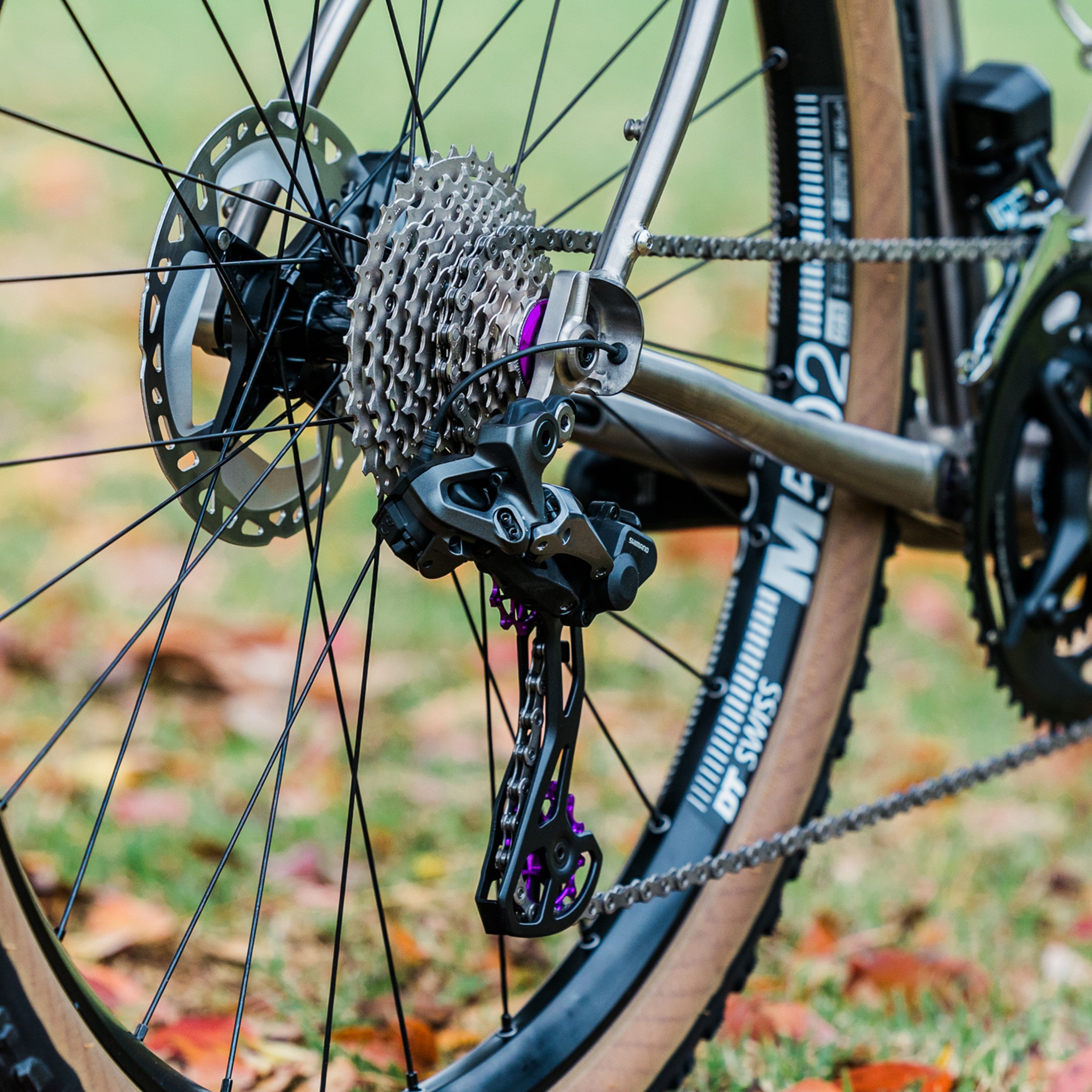 Close-up of a violet Garbaruk cassette lockring fitted to a Bossi titanium bike, demonstrating clean integration with cassette plus a pop of colour for the drivetrain