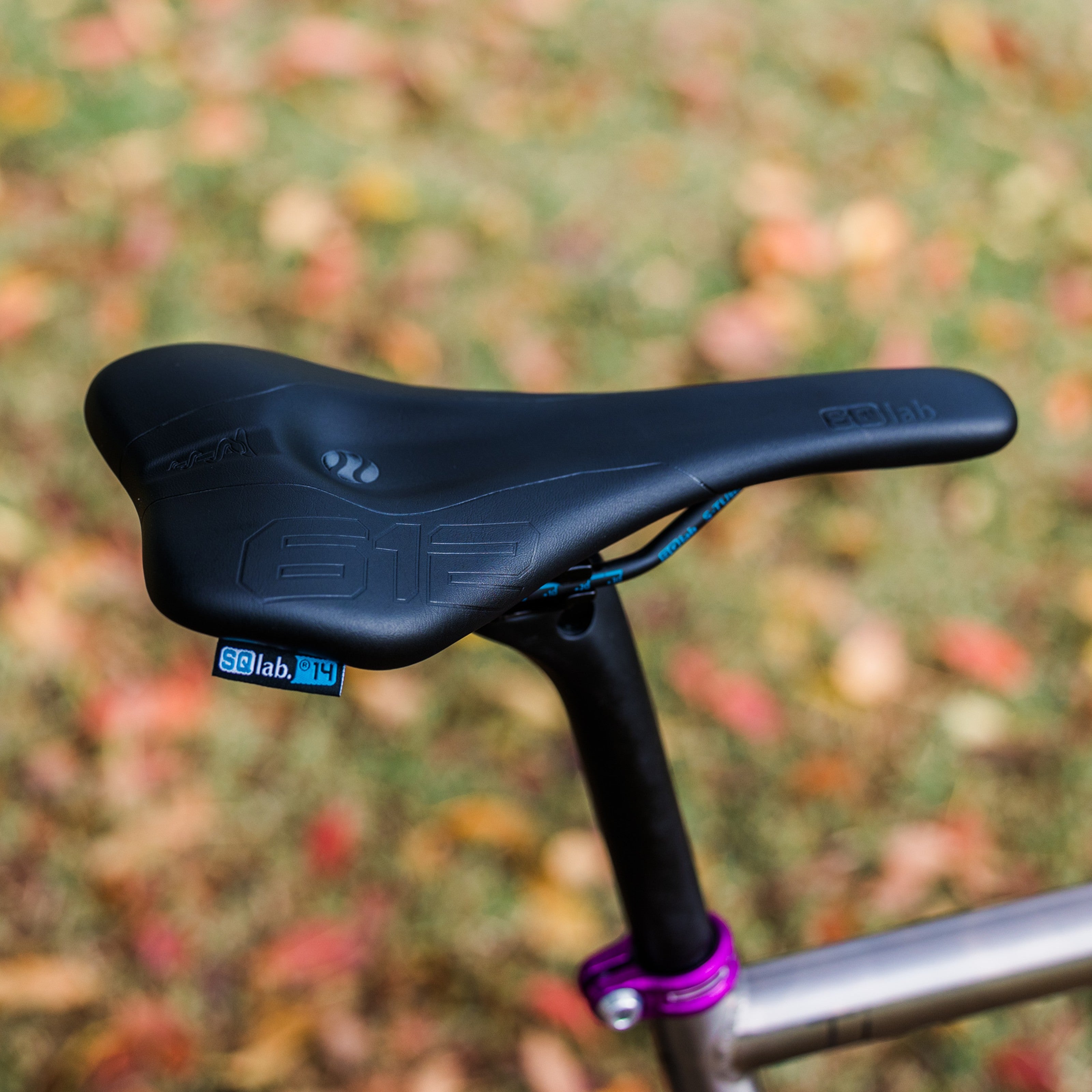 SQLab 612 Ergowave saddle installed on a titanium Bossi bike, photographed outdoors with natural greenery in the background
