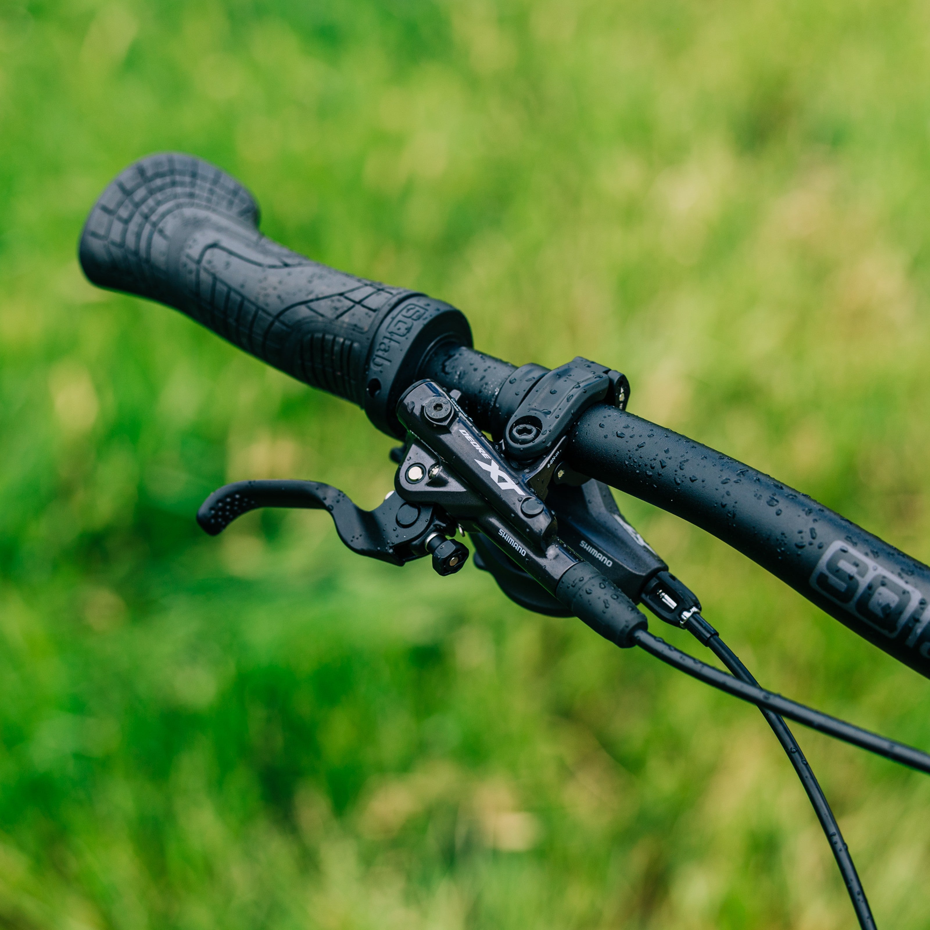 SQLab 710 grips installed on an SQLab handlebar, photographed outdoors with leafy background on a rainy day