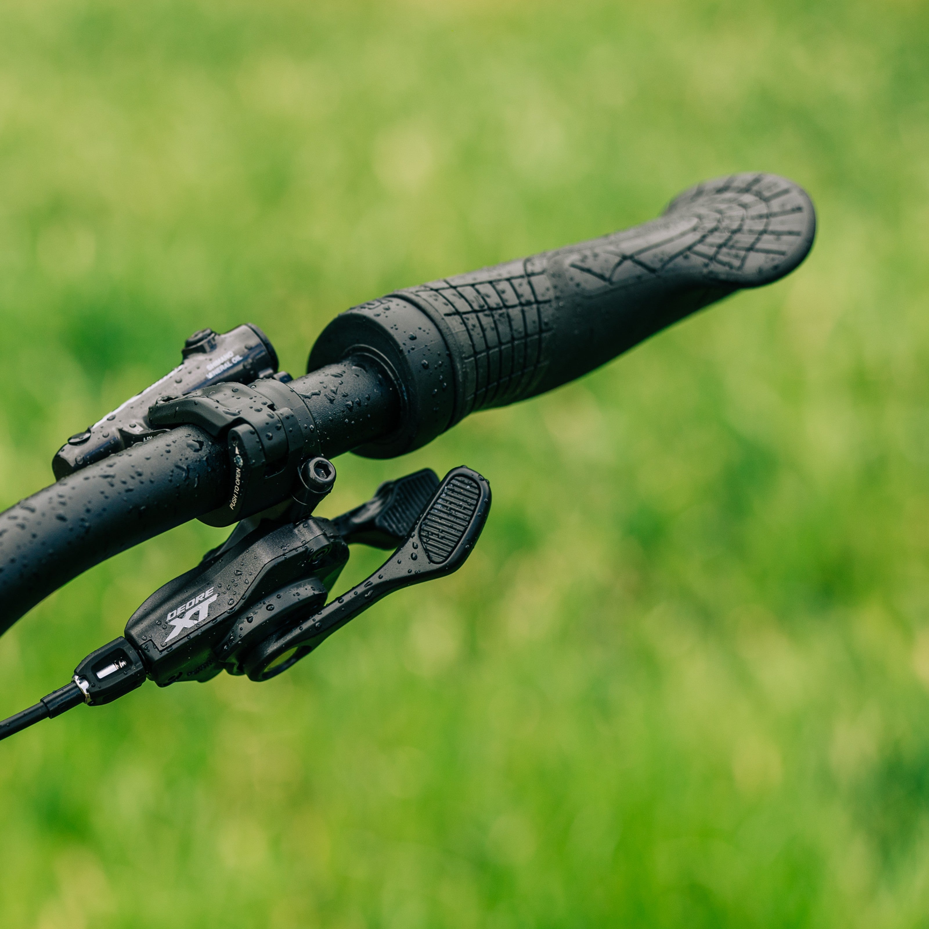 SQLab 710 grips installed on a custom-built bike, photographed outdoors on a rainy day, leafy background