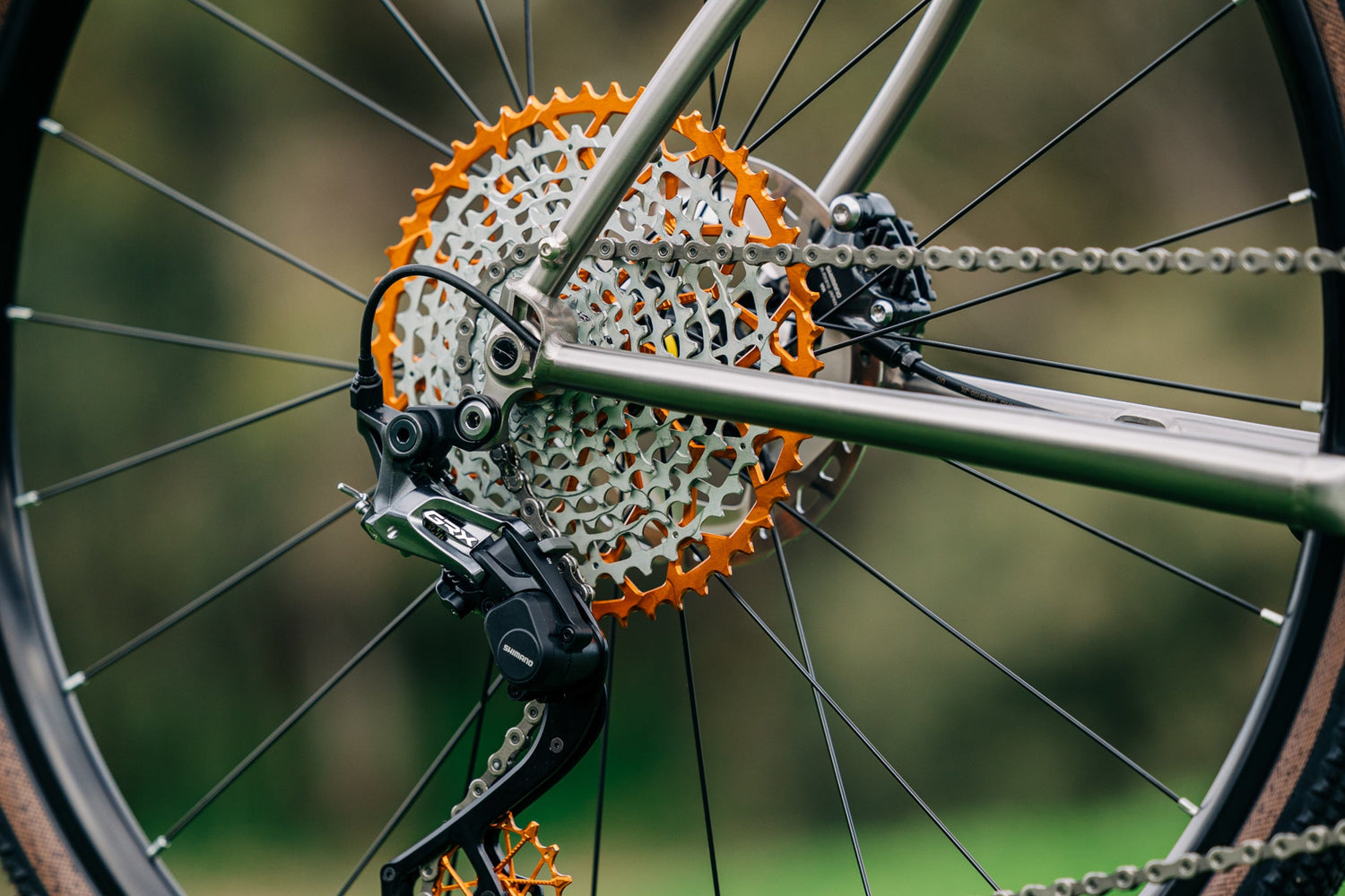 An orange Garbaruk cassette fitted to a titanium gravel bike, photographed outdoors