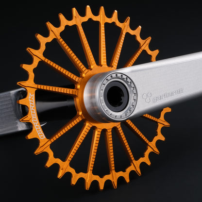 Garbaruk DM MTB chainring in orange, designed for mountain bike cranksets, showing precise CNC machining, mounted to a silver Garbaruk crankset