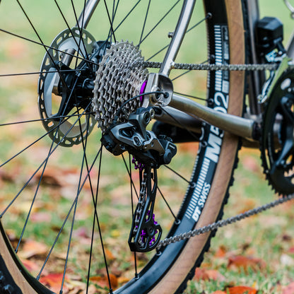 Close-up of a violet Garbaruk cassette lockring fitted to a Bossi titanium bike, demonstrating clean integration with cassette plus a pop of colour for the drivetrain