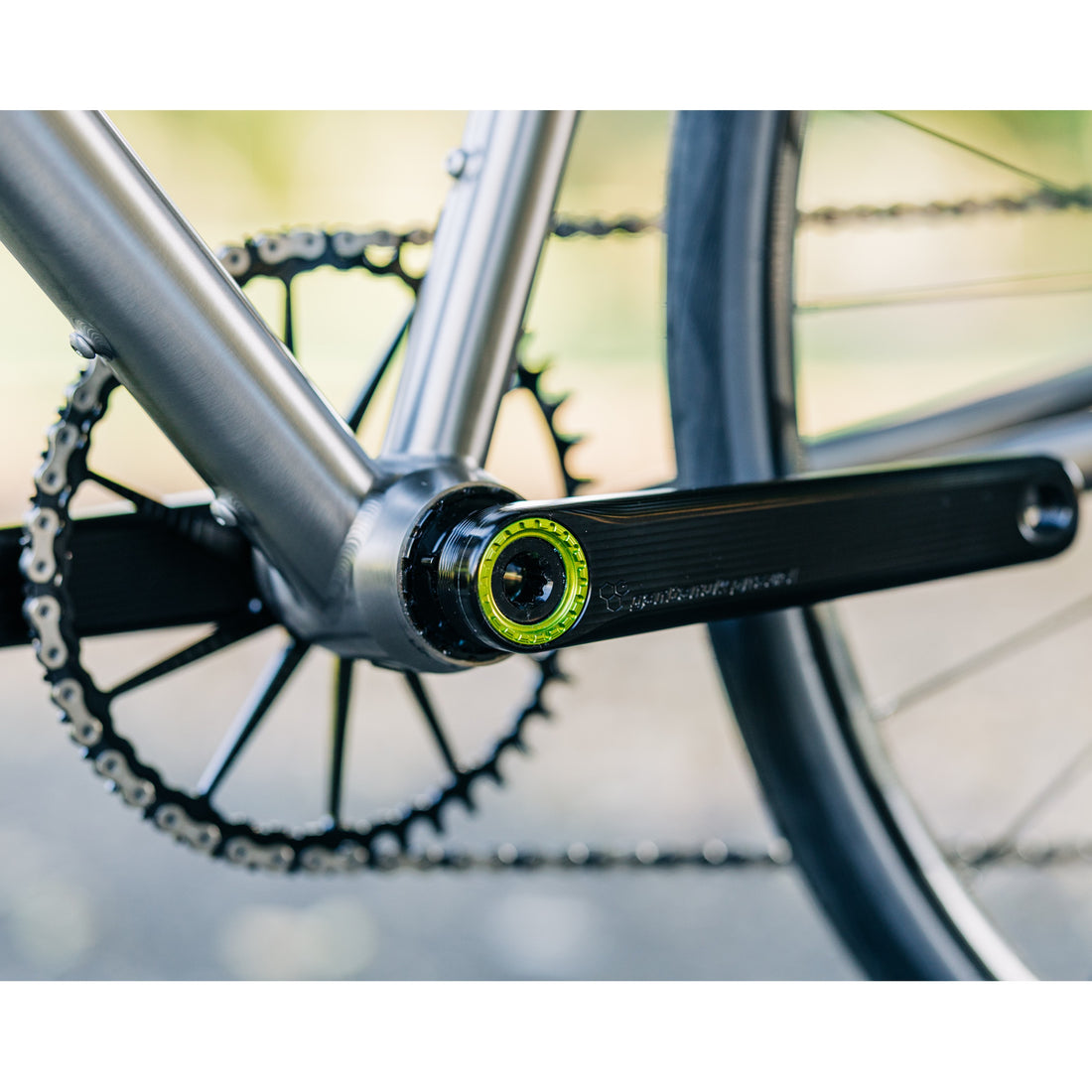 Garbaruk silver crankset with a black Garbaruk chainring installed on a titanium Bossi gravel bike, photographed outdoors to showcase high-end componentry