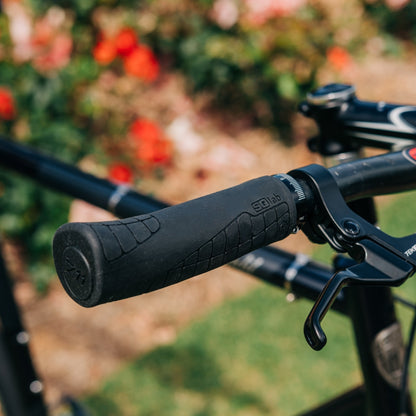 Close up of SQLab 711 grip installed on a flat bar commuter bike, photographed in a rose garden